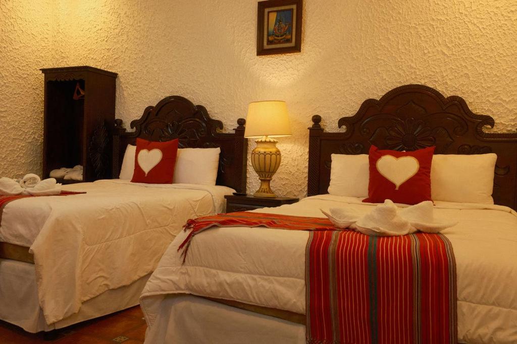 a hotel room with two beds with red and white pillows at Hotel Taa' Tiin in San Juan La Laguna