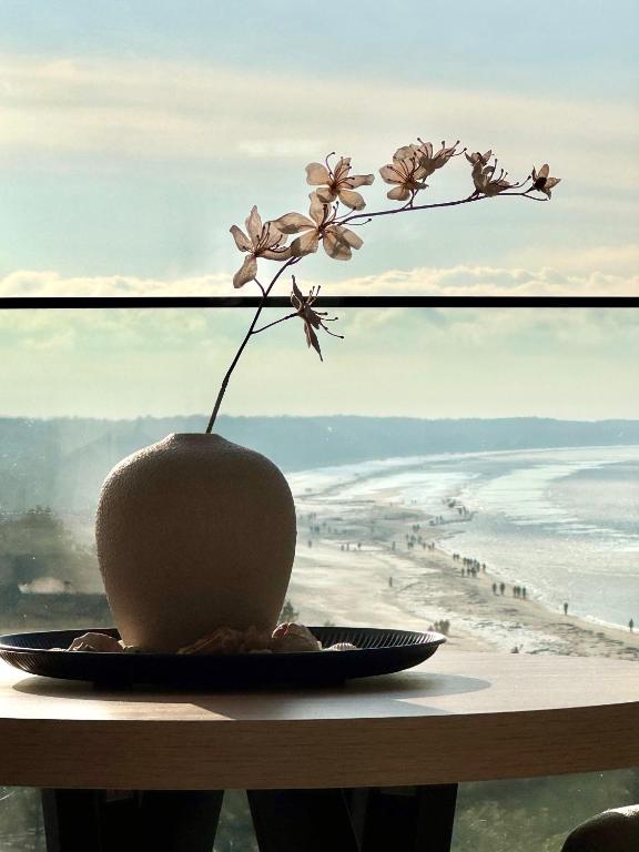 a vase of flowers on a table with a view of the beach at Baltic Infinity Suite 529 - SPA & Pool Access in Międzyzdroje