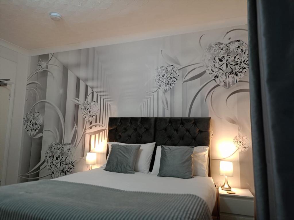 a bedroom with a large bed with flowers on the wall at Prestige Guest House Cambridge Modern Ensuite Rooms in Cambridge