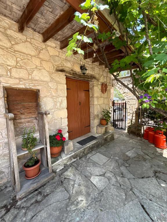 a stone house with a wooden door and potted plants at Lantana Stone House in Lemona