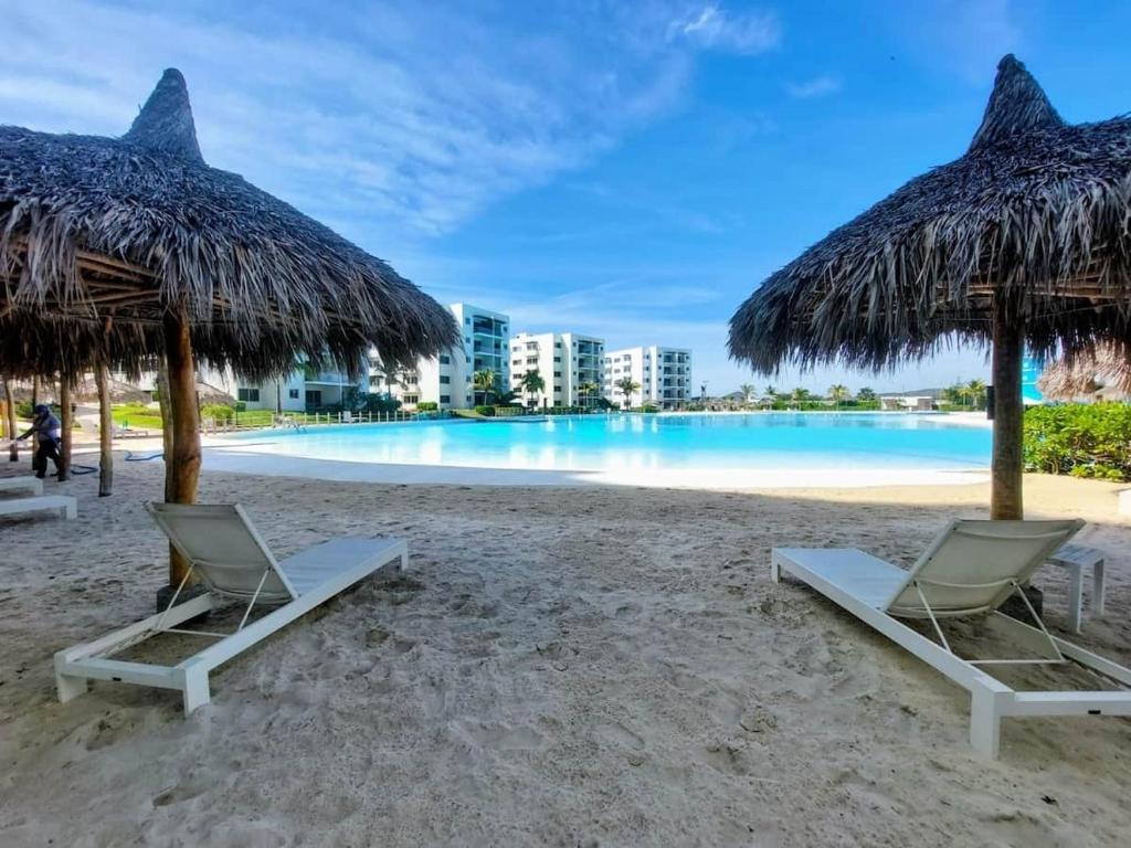 a beach with two chairs and straw umbrellas at Apartment with balcony overlooking crystal-clear lagoon and in Mazatlán