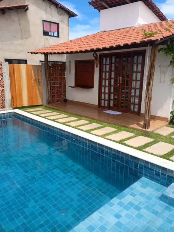a villa with a swimming pool in front of a house at Chalé Brisa da Mata Baia Formosa in Baía Formosa