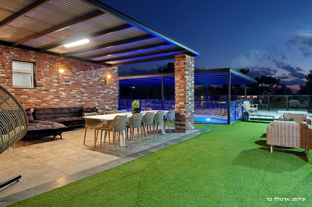 a patio with green grass and a table and chairs at וילת היוצר in Ya‘ara