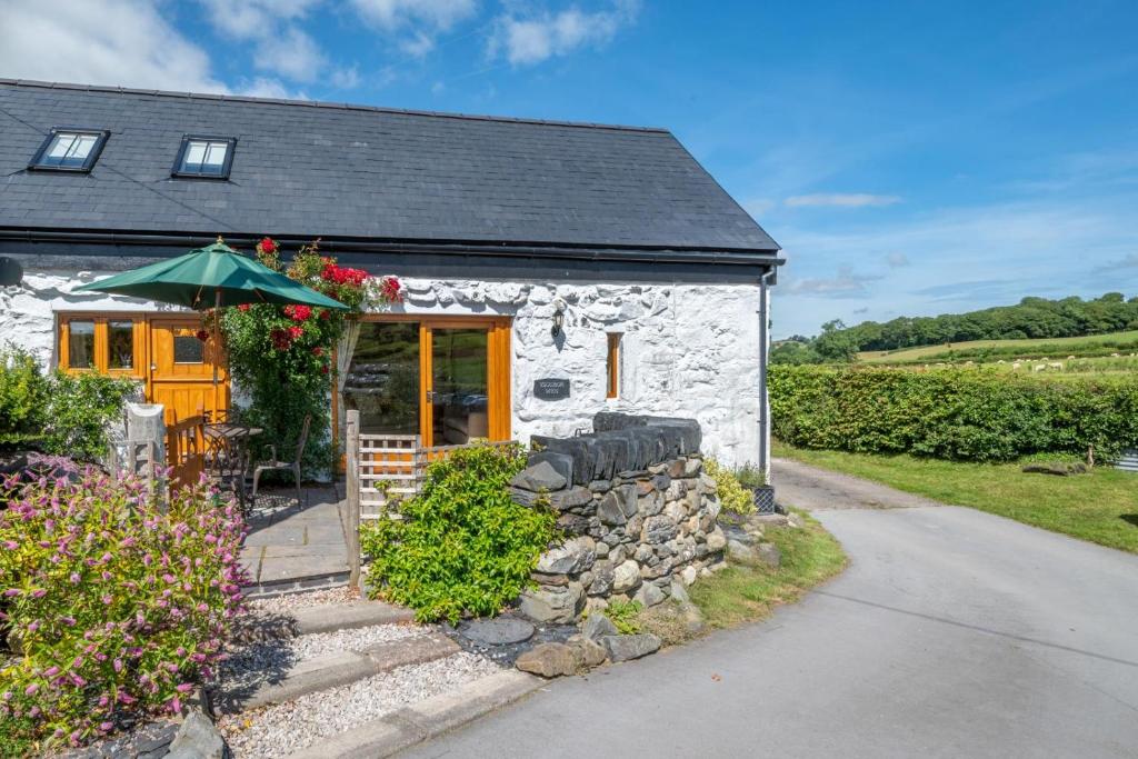 a small stone house with an umbrella and flowers at 3 Bed in Llanrwst oc-wag689 in Llanrwst