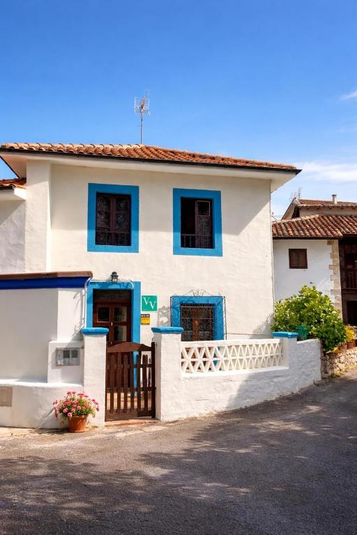 a white house with blue windows and a gate at La casina de Barro in Llanes