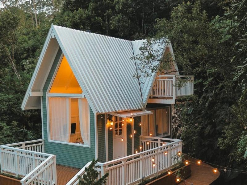a small house with a porch and a deck with lights at Chalé Villa Mount in Timbe do Sul