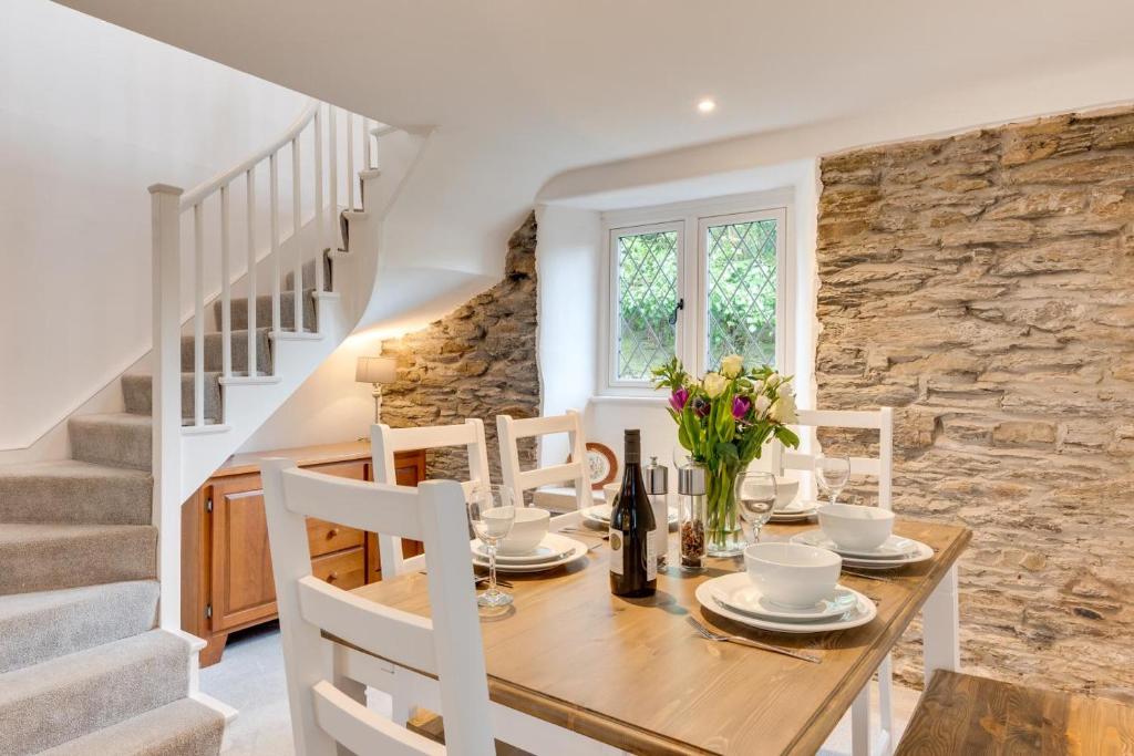 a dining room with a table and chairs and a stone wall at 3 Bed in Fowey oc-1cobbs in Fowey