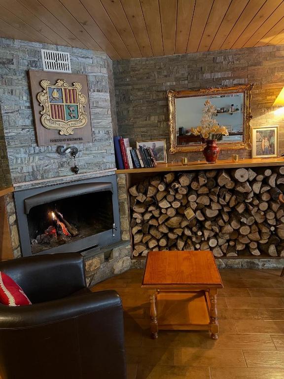 a living room with a fireplace and a couch and a table at Hotel Les Truites Adults only in Pas de la Casa