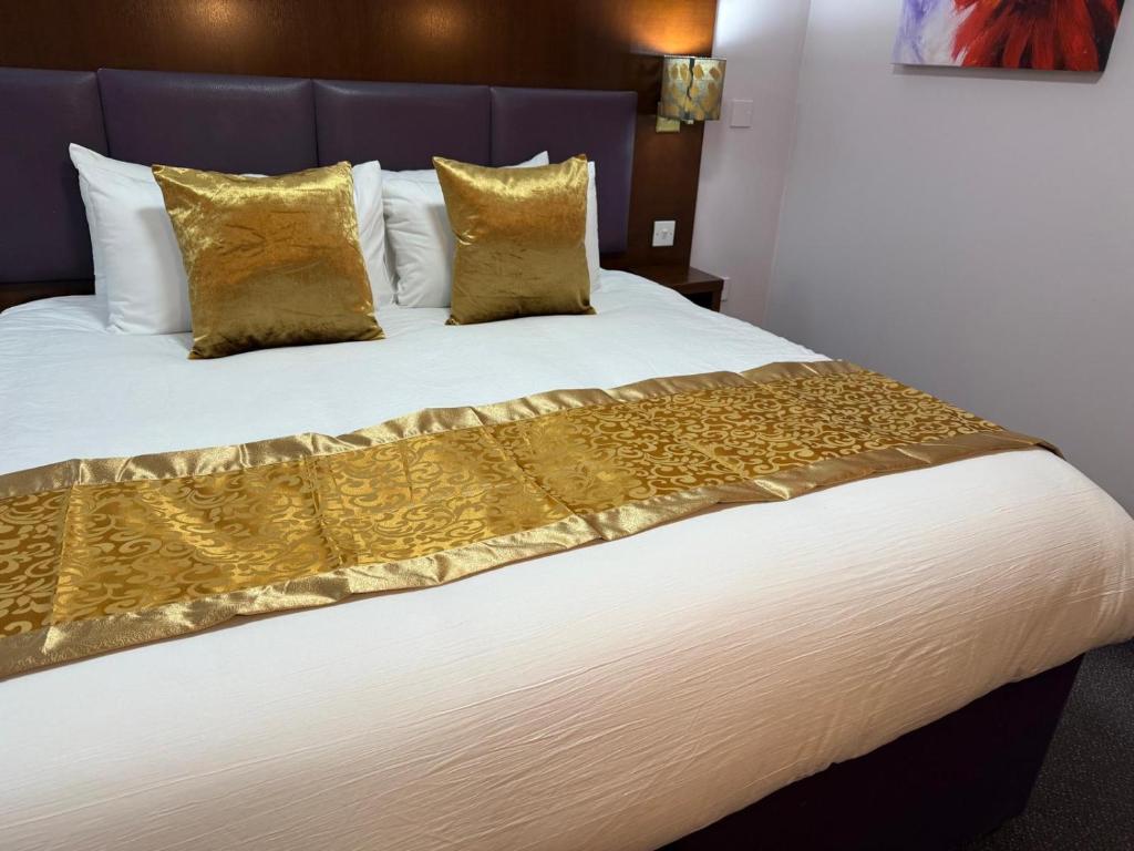 a bedroom with a large bed with yellow pillows at Quality City Hotel Restaurant Free Parking in Upton Warren