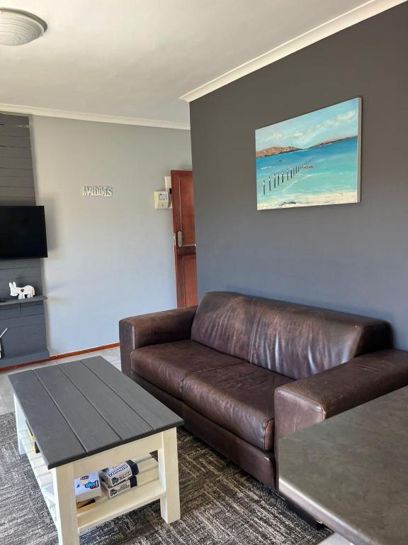 a living room with a brown leather couch and a table at Flamingo Park D1 Langebaan in Langebaan