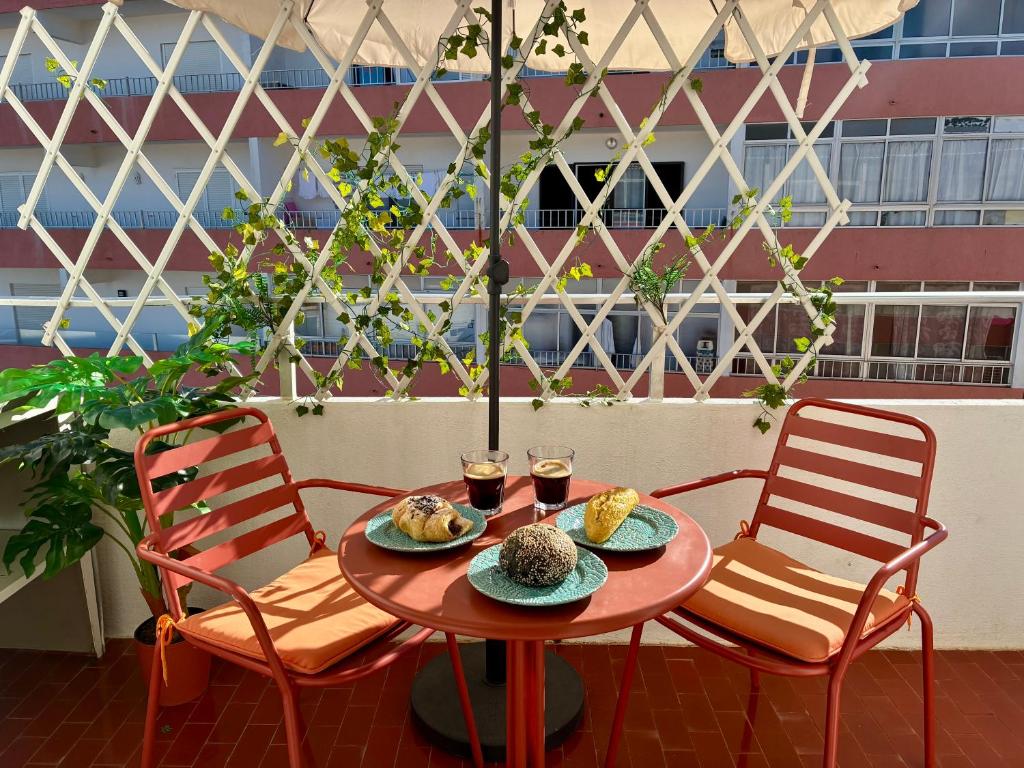two chairs and a table with food and glasses of wine at Refúgio na Praia de Santa Cruz- A poucos passos da praia, surf e restaurantes in Santa Cruz