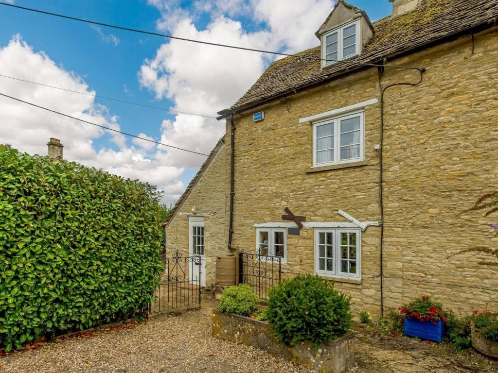 an old stone house with a hedge in front of it at 2 Bed in Lechlade oc-40194 in Langford