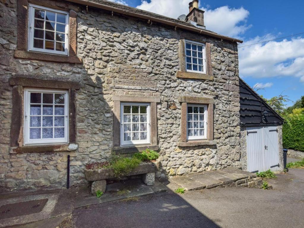 an old stone house with a white door and windows at 2 Bed in Matlock oc-81043 in Winster