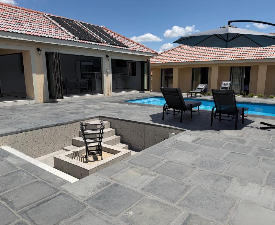 a patio with chairs and a table next to a pool at M & N Guest House in Ermelo