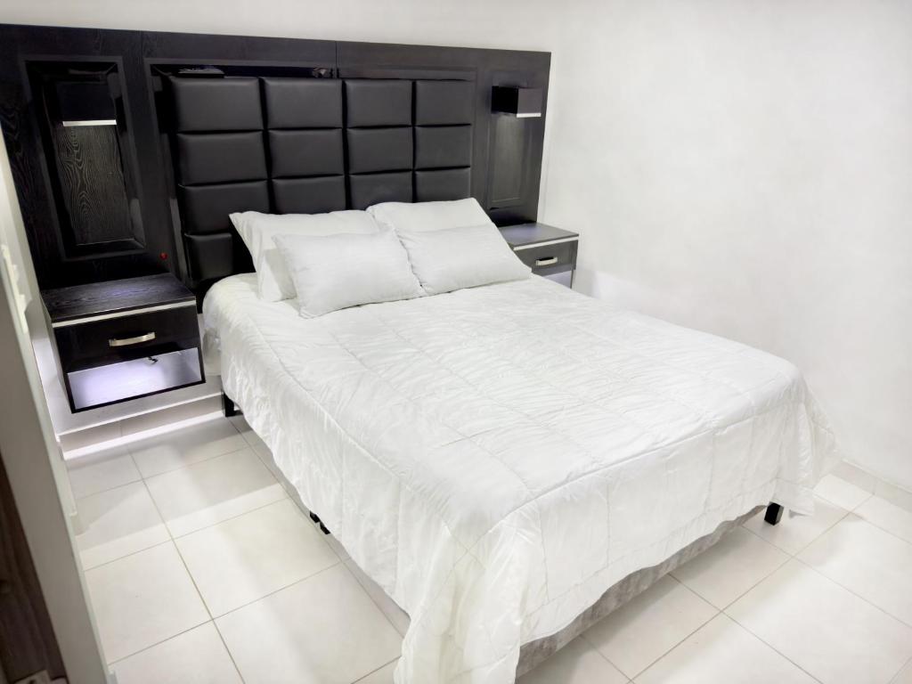 a white bed with a black headboard in a bedroom at Apartamento Premier in Ibagué