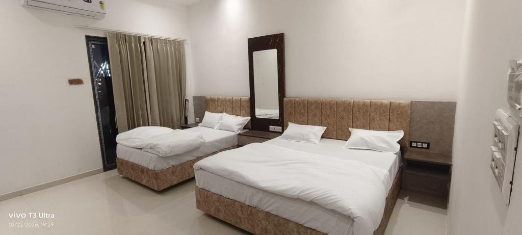 a bedroom with two beds and a mirror at Hotel Ramlalla in Khātu