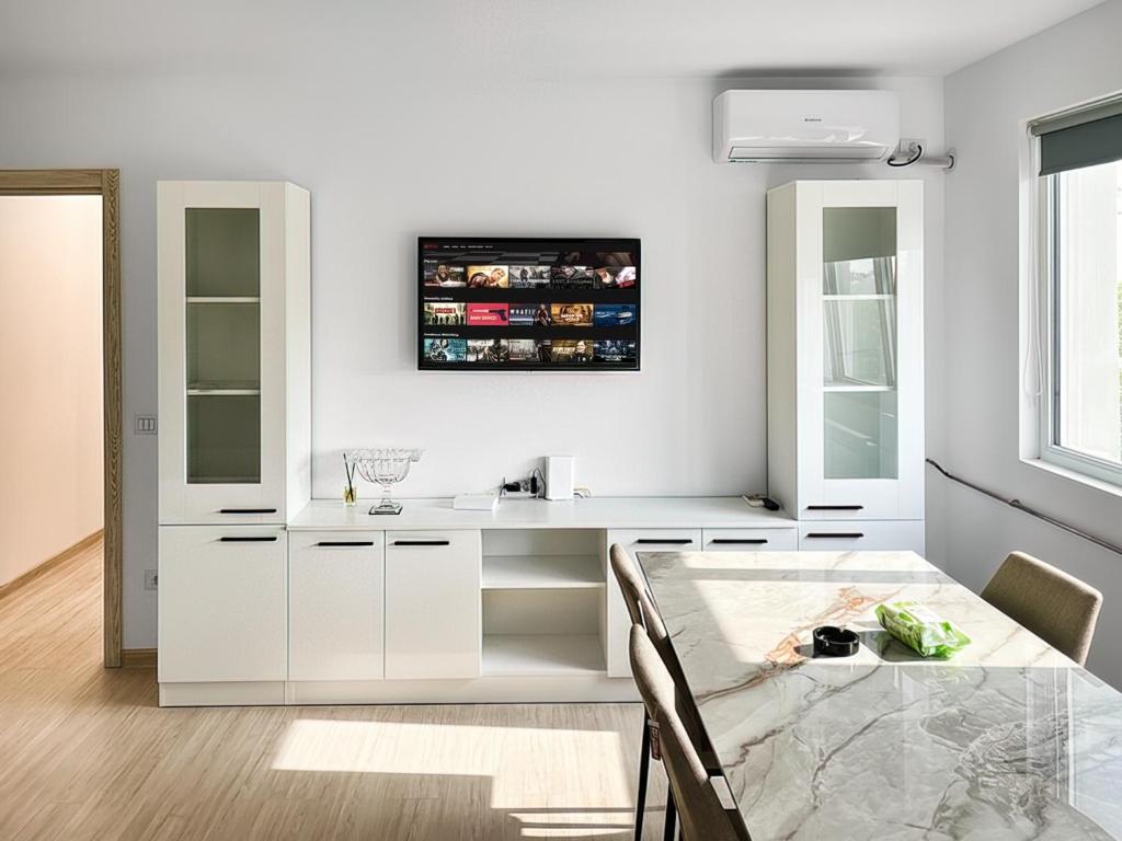 a kitchen with a table and a tv on the wall at Apartament Karim in Drobeta-Turnu Severin