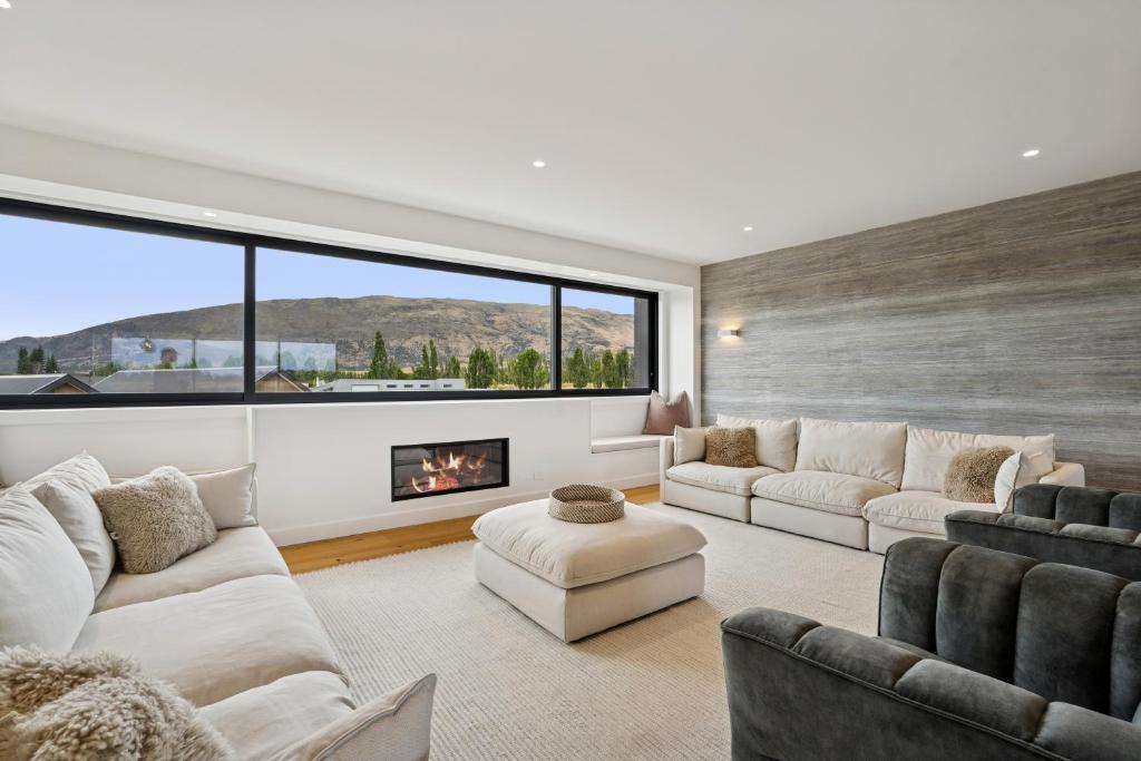 a living room with white furniture and a fireplace at Rubus St Residence by Sothebys Luxury Rental Homes in Wanaka