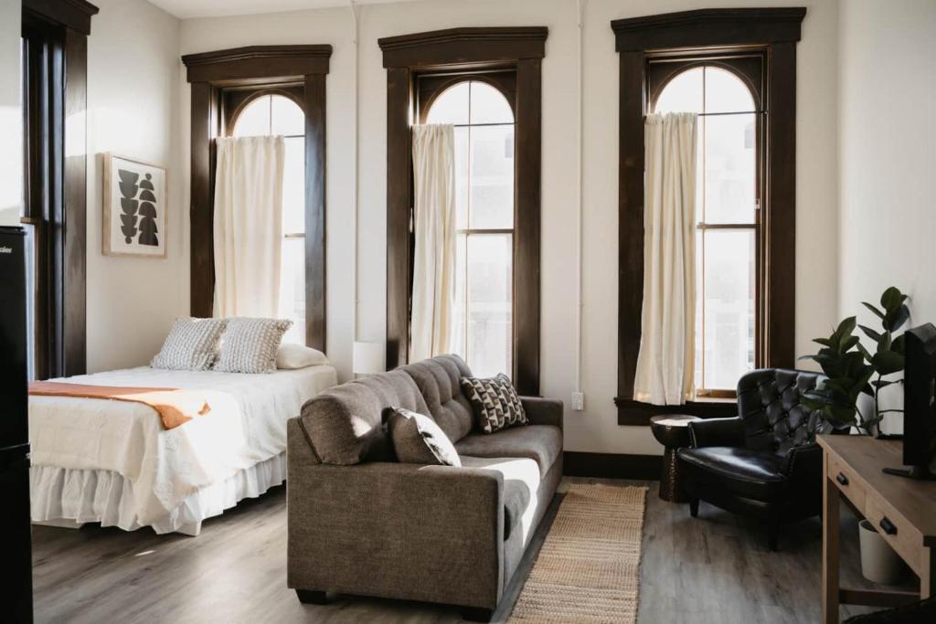 a bedroom with a couch and a bed and windows at The Neighborhood Lofts in Greencastle