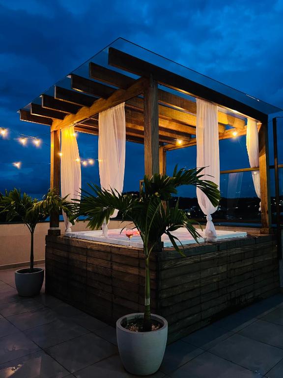 a patio with a gazebo and two palm trees at Jacuzzi com vista! Espaço para eventos in Betim