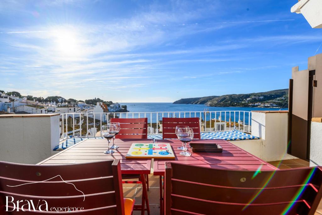 a table with wine glasses on a balcony overlooking the ocean at Es Forn - Vistas panorámicas a la bahía I terraza privada I 5 dormitorios I chimenea I centro histórico I Brava Experience in Cadaqués