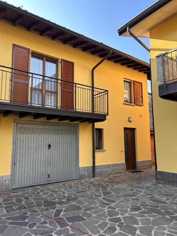 a yellow house with a balcony and a garage at Casa vacanze Orchidea in Treviolo