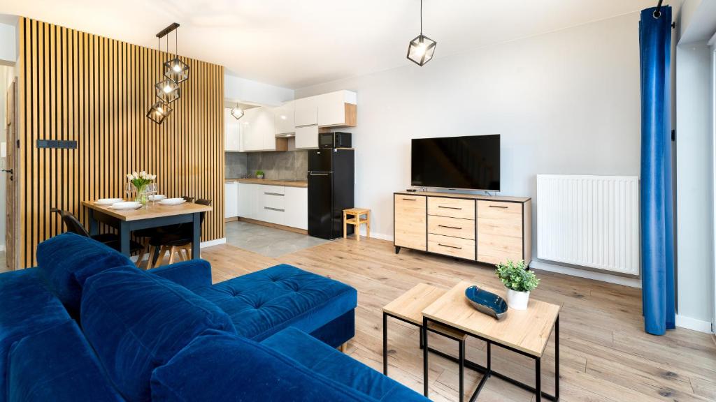 a living room with a blue couch and a kitchen at Apartamenty Ewa in Karpacz