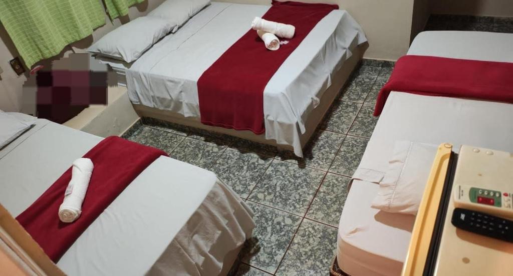zwei Betten mit roter und weißer Bettwäsche in einem Zimmer in der Unterkunft Ferrari's Hotel in Birigui