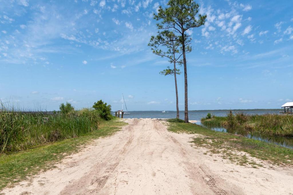 a dirt road with two trees next to the water at Stunning 3br/25ba, Pet Friendly, sleeps 12 in Orange Beach