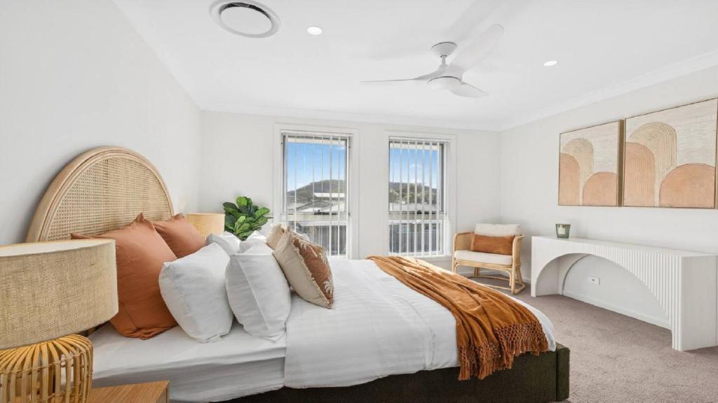 a bedroom with a bed and a desk and windows at The Haven - Ettalong in Ettalong Beach