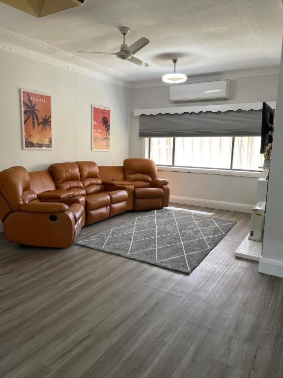 a living room with a brown leather couch at StevieNic's Dig's in Broken Hill