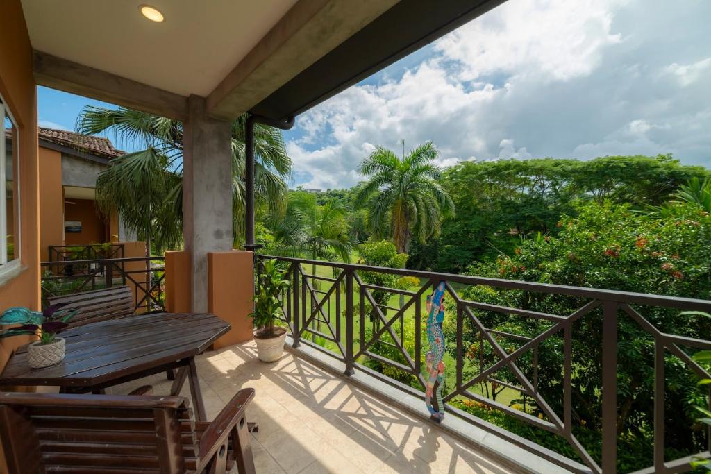 a balcony with a wooden table and chairs and trees at Veranda 4B 3 bdr Golf Course View in Los Suenos in Herradura