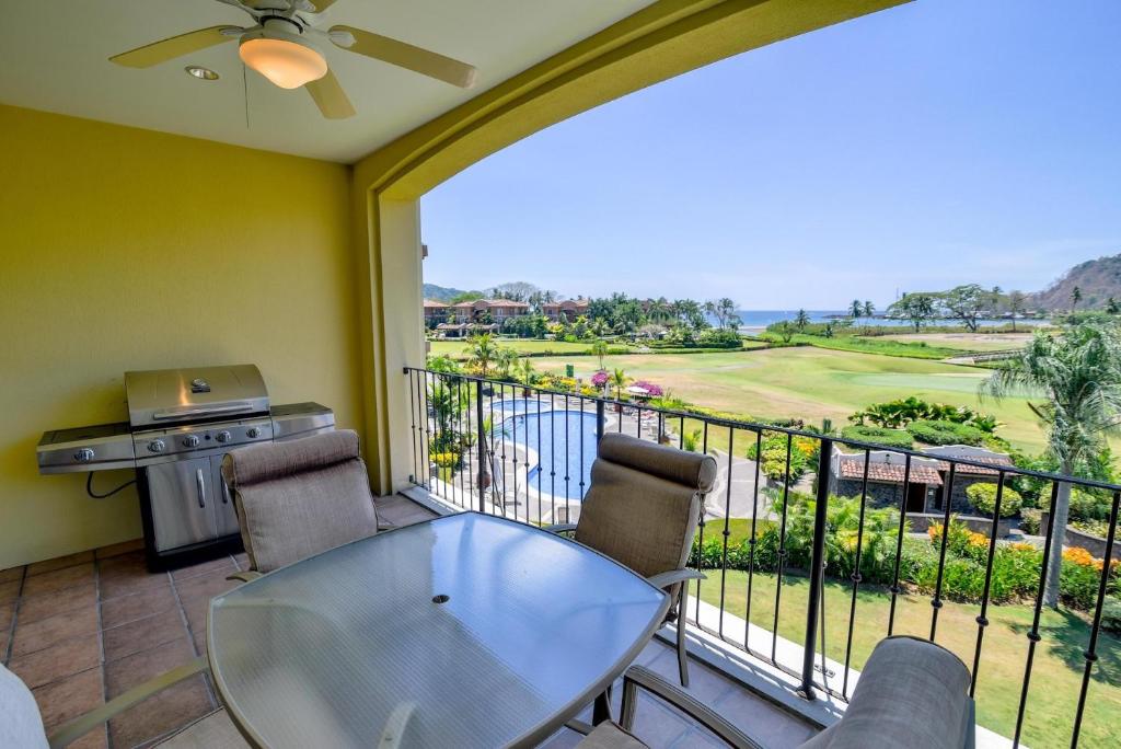 a balcony with a table and chairs and a view of a golf course at Del Mar 3C 3 bdr Ocean View in Los Suenos in Herradura