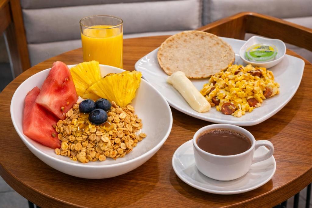 a table with two plates of food and a cup of coffee at Hotel Plaza Doce in Pereira