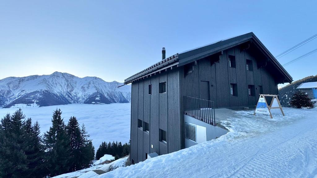a building in the snow with mountains in the background at Chalet Talblick in Riederalp