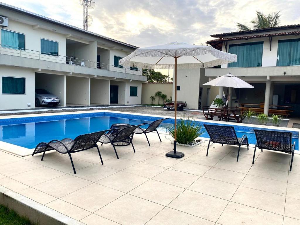 a patio with chairs and an umbrella next to a pool at Cacao's Guaibim Residence in Valença