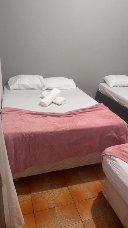two twin beds in a room with red and white sheets at Pousada Bem estar in Divinópolis