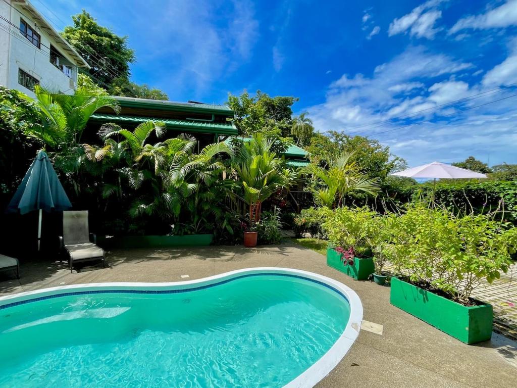 a swimming pool in front of a house with plants at Finca Los Mangos in Manuel Antonio