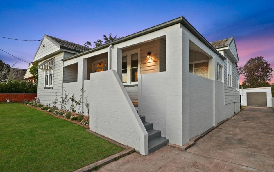 a white house with a staircase in front of it at Aveline Cottage in Cessnock