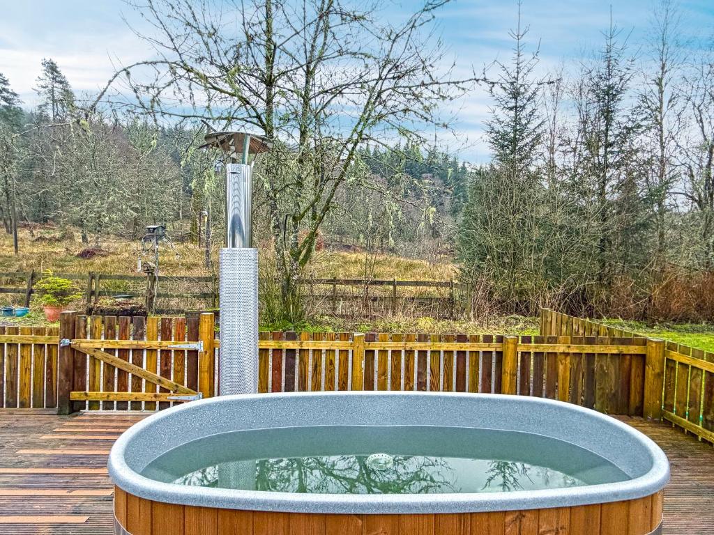 a hot tub on a deck with a wooden fence at Bonnie's Bothy in Port of Menteith