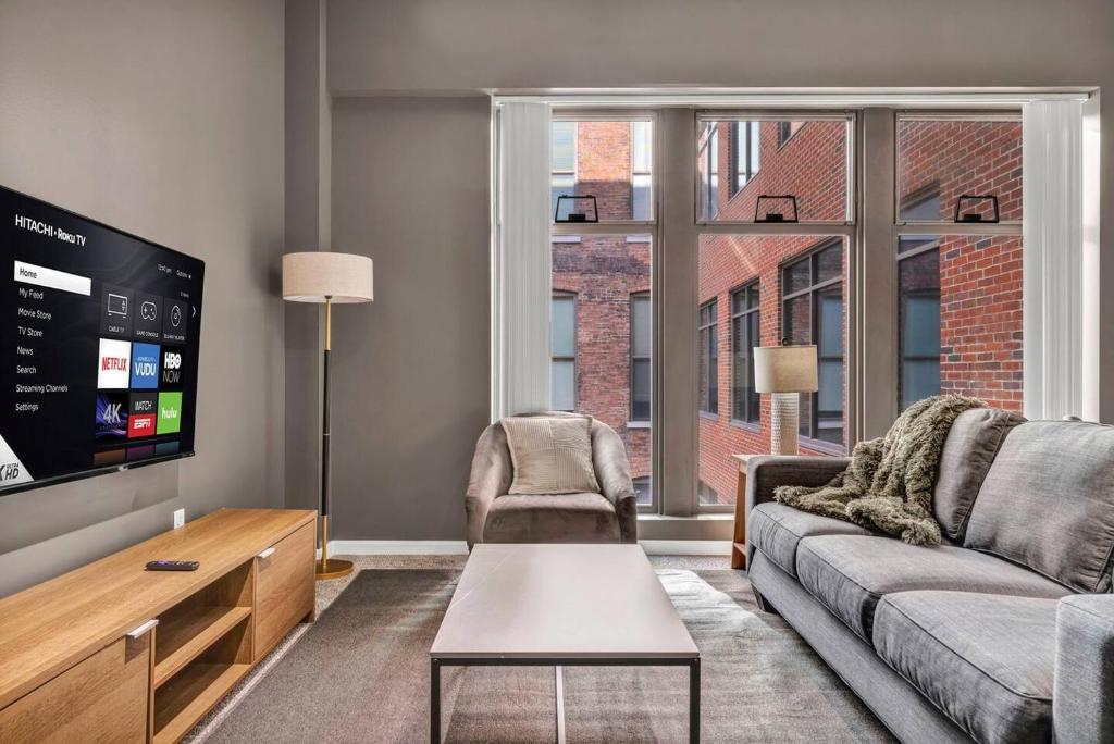 a living room with a couch and a flat screen tv at Luxe Downtown Condo • Pool Table & Parking in Cleveland