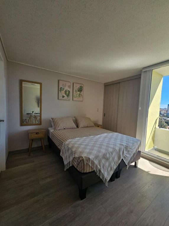 a bedroom with a bed and a large window at Modern fully equipped studio with parking in Concepción