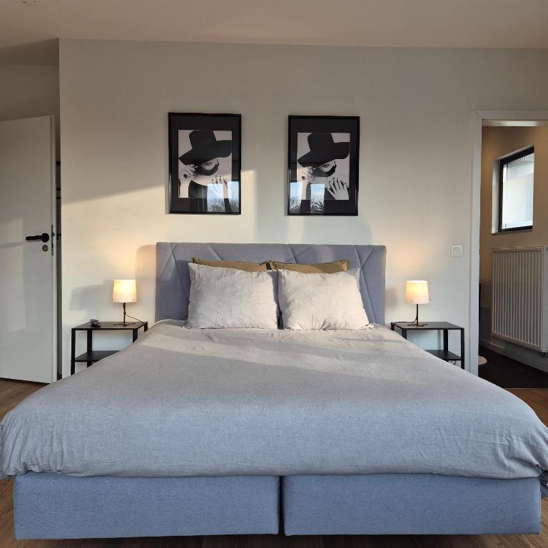 a bedroom with a large bed with three pictures on the wall at Orient Herent - Boetiekhotel in Herent