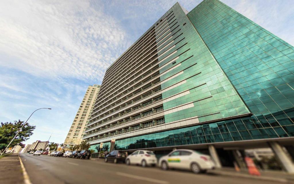 a tall building with cars parked in front of it at Flat com vista espetacular no centro de Brasília Vision Work and live in Brasília