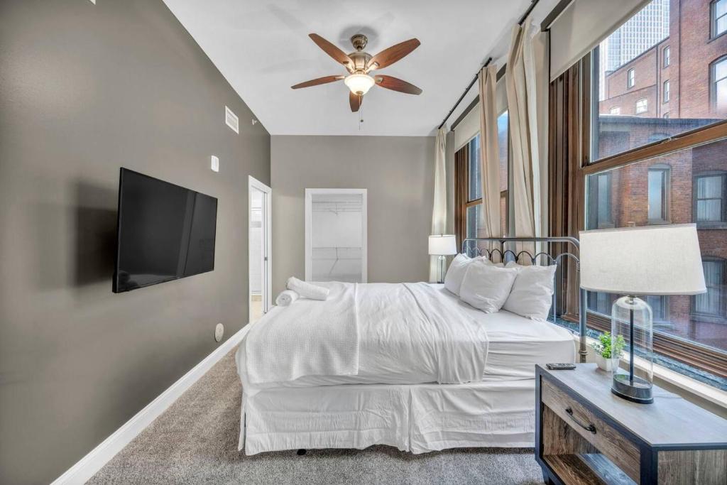 a bedroom with a bed with a ceiling fan and a tv at Central Downtown Loft | Parking•Gym•Security in Cleveland