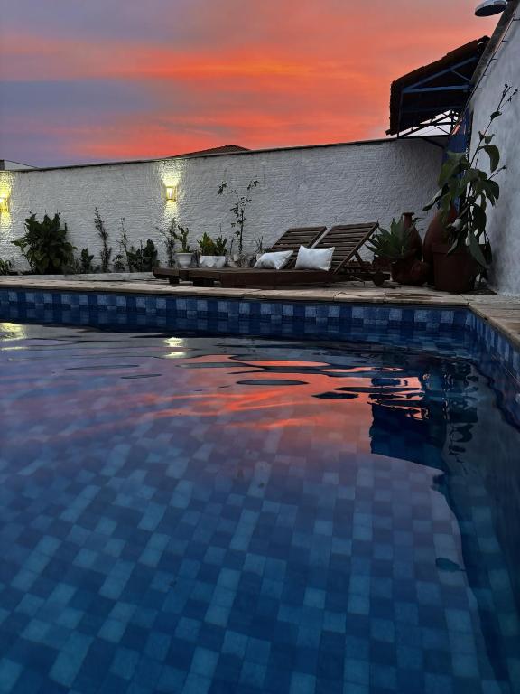 a swimming pool with a sunset in the background at Pousada Villa Grega de Piri in Pirenópolis