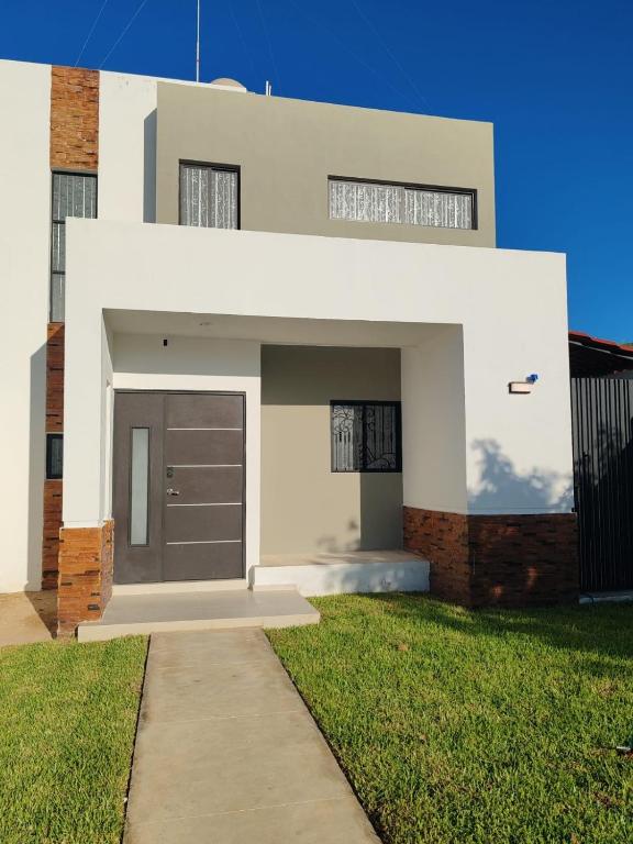 a white house with a door and a grass yard at Casa Havana Mid in Mérida