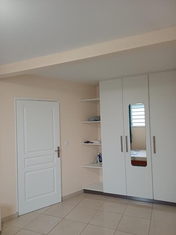a white room with a door and a mirror at Santa Marta in Rivière-Pilote