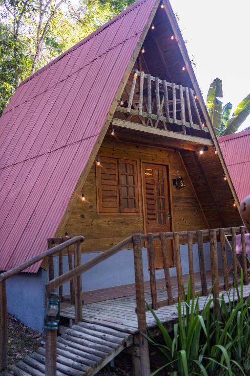 a small house with a red roof and wooden stairs at Cabana Suiça 2 in Guaramiranga