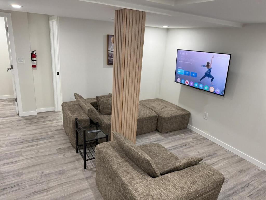 a living room with couches and a flat screen tv at Urban Haven Suite in Winnipeg